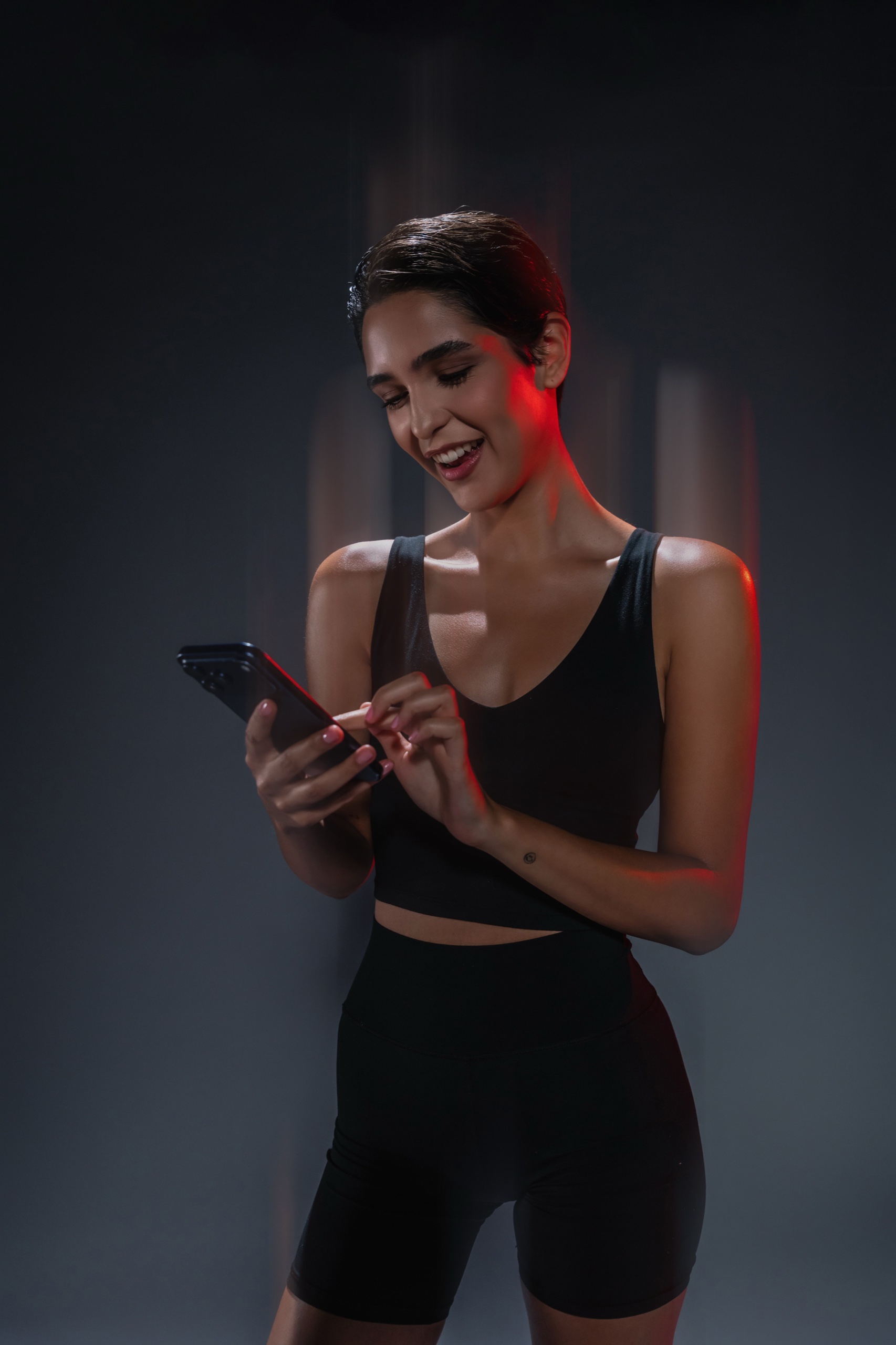 Athletin blickt auf ihr Smartphone im Studio